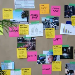 Lavagna con post-it e immagini su mobilità ciclistica. Parole in inglese facili come "Pricing", "Safety", "Location" e "Hygiene" sono scritte su post-it colorati.