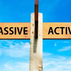 Cartello stradale con frecce "PASSIVE" e "ACTIVE" sotto un cielo azzurro. La scelta tra essere passivi o attivi è presentata.